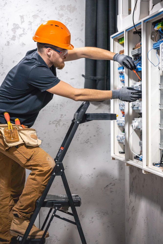 Male electrician working in a switchboard with fuses